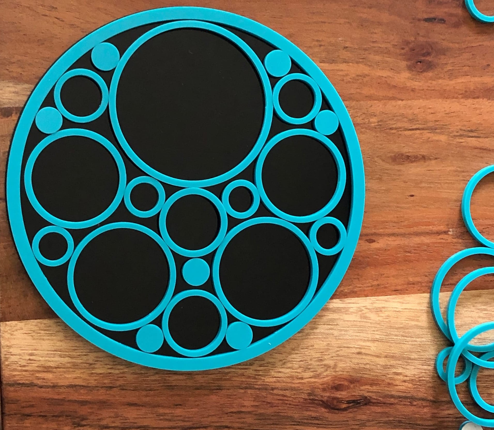 a laser cut black circle with smaller turquoise circles laid on top to make a gasket