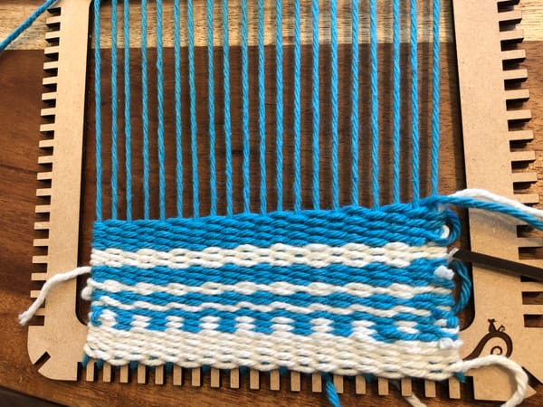 a laser cut loom with blue and white yarn