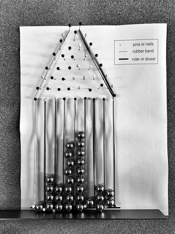 a quincunx made of pins and marbles