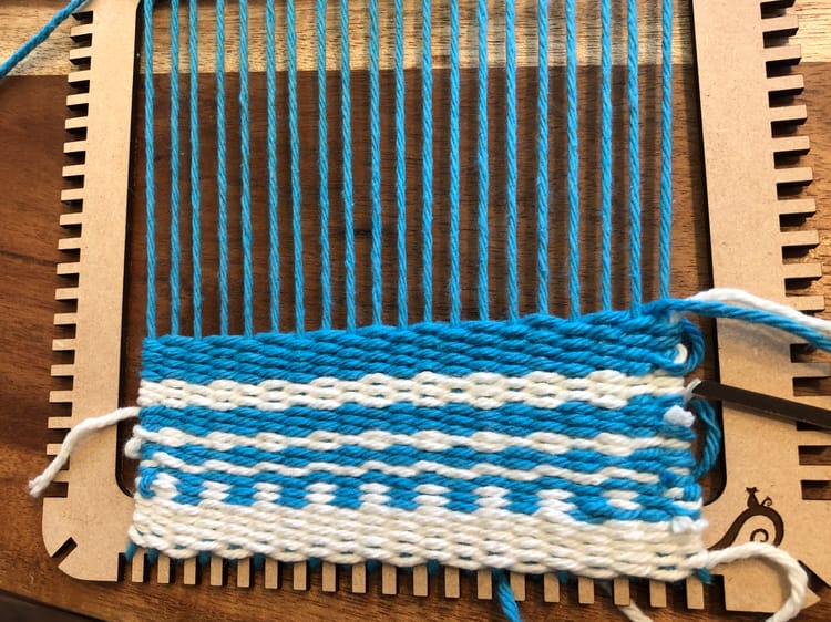 a laser cut loom with blue and white yarn