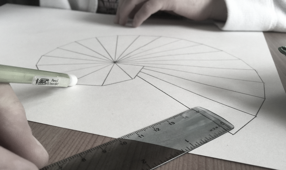 paper with spiral of Theodorus with two hands a pencil and a ruler