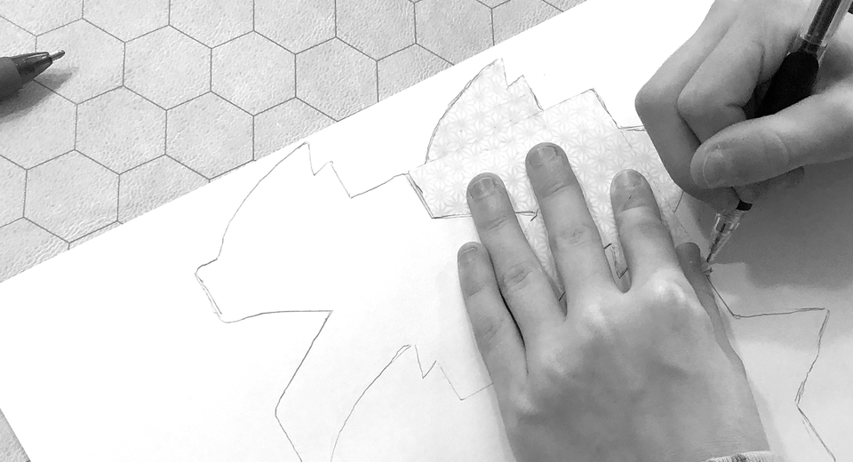 two hands copying a tessellation on paper