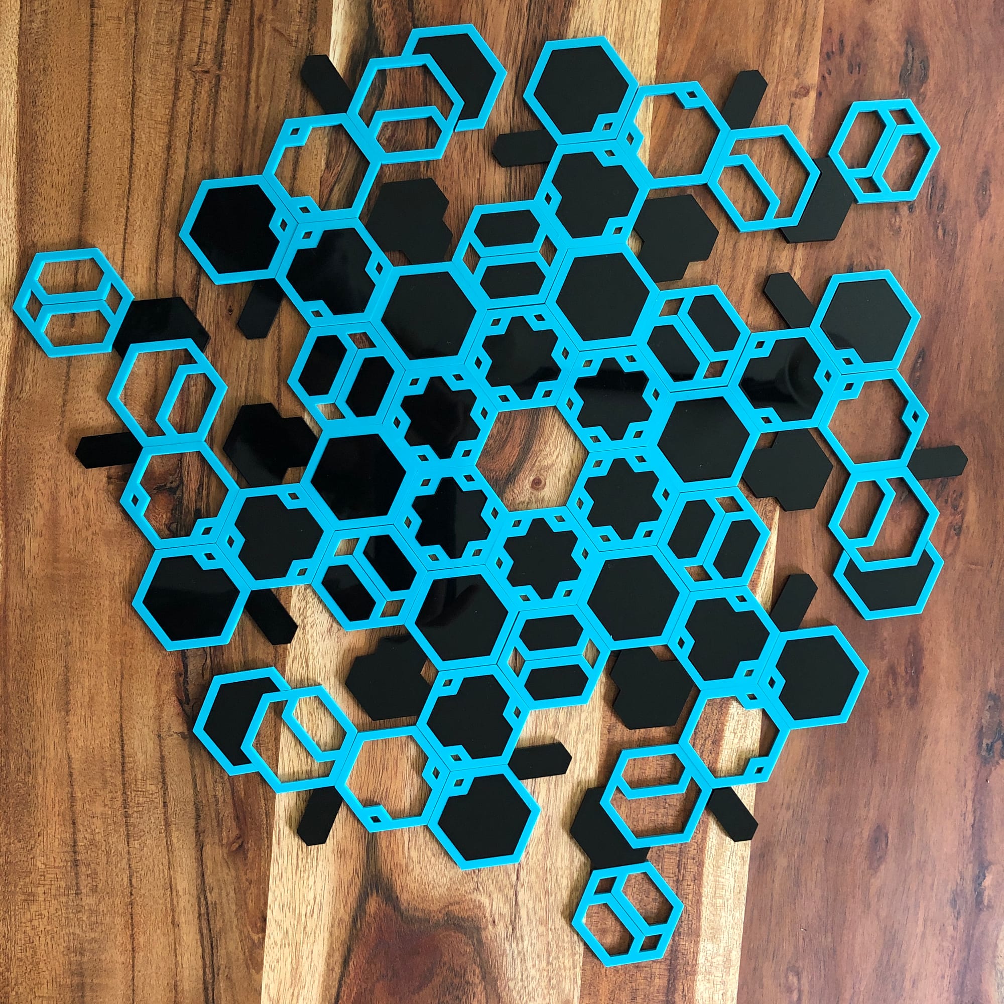 black and blue hexagonal tiles on a wooden surface placed with rotational symmetry